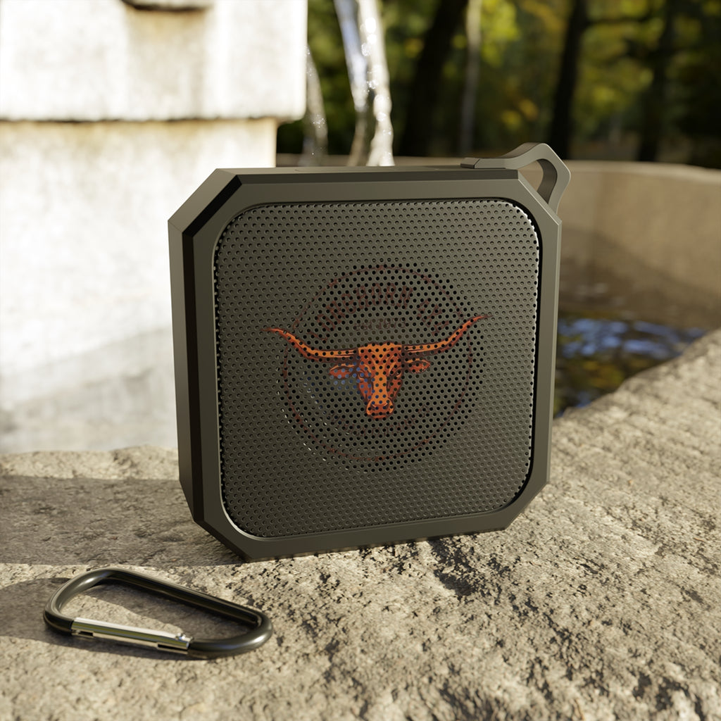 Black portable speaker with a logo on a stone surface