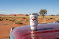 White tumbler with a longhorn 4x4 logo on a sitting on a ute bonnet in the Australian desert background